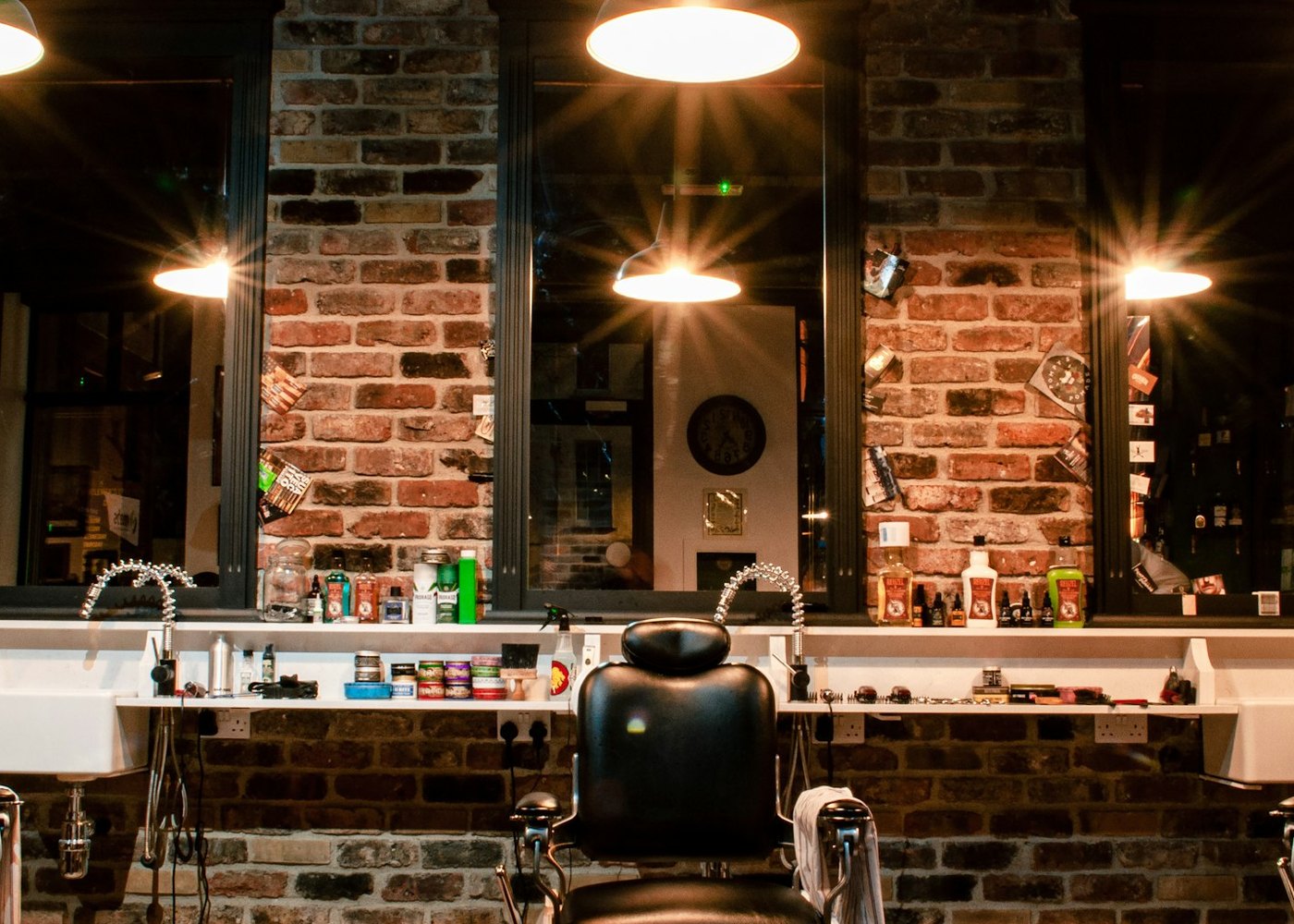 The row of barber's chairs and the mirrors along the brick wall, under the shop's pendant lamps