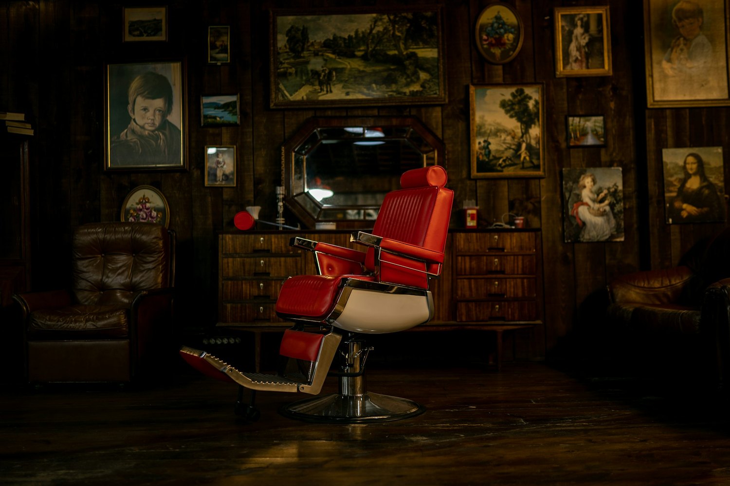 The red chair in the back room, the wall behind it hung with framed pictures